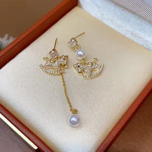 Macro view of asymmetrical rocking horse earrings with zircon and pearls in a jewelry box.