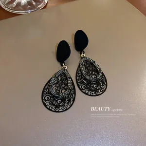 Detail showing black teardrop earrings with intricate filigree and crystal accents