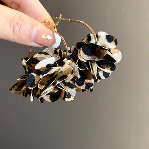Close-up of fabric leopard print flower hoop earrings with tiered petals.
