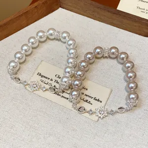 Close-up of elegant pearl bracelets with sparkling zircon flower charms detail