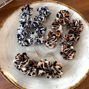 Close-up view of bohemian leopard print fabric flower earrings displayed on a ceramic plate
