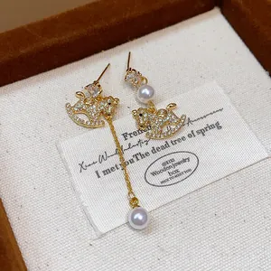 Close-up of asymmetric gold-plated rocking horse earrings with CZ and pearl tassels.