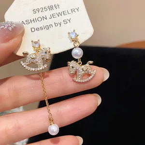 Close-up detail of gold-plated rocking horse earrings with sparkling zircons and pearls