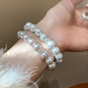 Close-up detail of elegant pearl bracelet with sparkling zircon charm on wrist