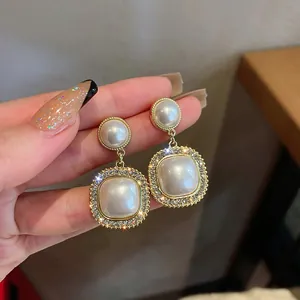 Close-up detail of elegant gold-toned geometric earrings with pearls and crystals