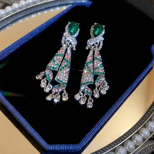 Close-up of elegant teardrop dangle earrings featuring green and pink zirconia tassel design
