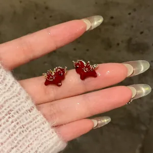 Detailed view of red enamel zodiac horse stud earrings with delicate gold wings