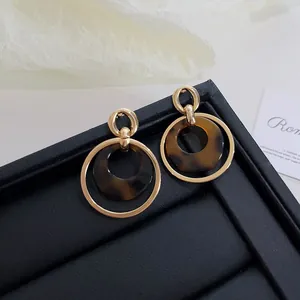 Macro detail of vintage tortoiseshell resin earrings featuring elegant gold circular metal frames