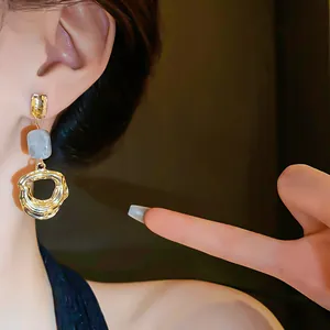 Detailed close-up of vintage Maillard style gold hoop earrings with marble effect bead accent