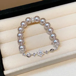 Detail view of elegant pearl bracelet with zircon flower charms on cream velvet display