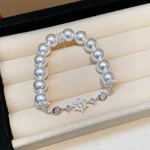 Close-up of elegant zircon flower pearl bracelet displayed in a cream jewelry box