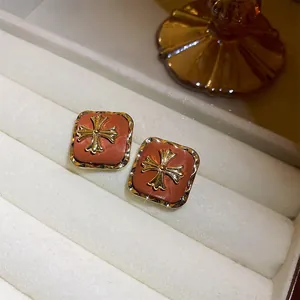 Vintage Maillard brown square stud earrings with golden cross detail on white tray