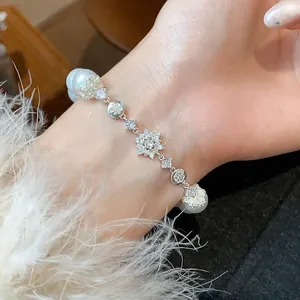 Detailed view of a French style zircon flower pearl bracelet on a woman's wrist