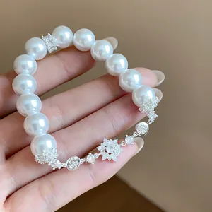 Detailed view of a French zircon flower and white pearl bracelet displayed on a hand