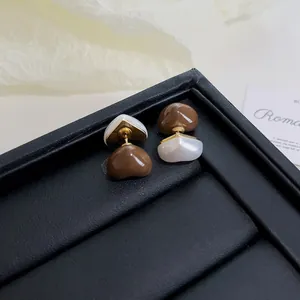 Macro view of vintage heart-shaped stud earrings with brown and white enamel finish