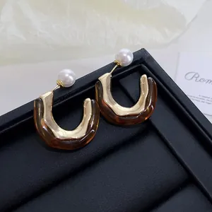 Detail of vintage Maillard style brown resin earrings with gold metal and pearl stud