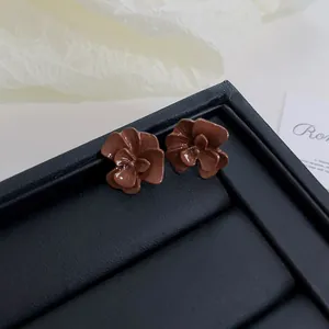 Close-up of vintage Maillard style glossy brown flower stud earrings on a black display tray.