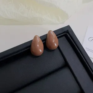 Detailed macro view of vintage brown bean-shaped stud earrings on black display stand