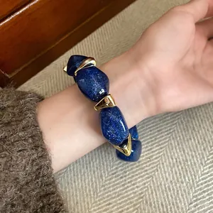 Elegant blue glitter acrylic oval beaded bracelet with gold-tone accents on wrist