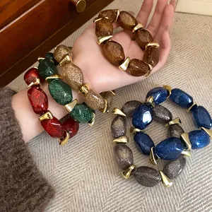 Detailed view of colorful glitter acrylic oval beaded bracelets with gold spacers