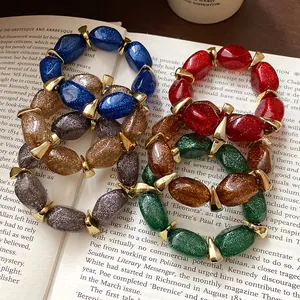 Detail of glittery oval acrylic beaded bracelets with gold spacers on a vintage book.