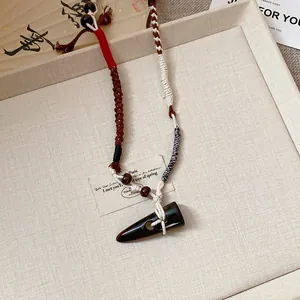 Close-up of a handmade ethnic woven necklace featuring a dark toggle-shaped pendant