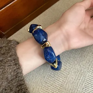 Macro view of a chunky blue glitter acrylic bead bracelet with irregular gold accents