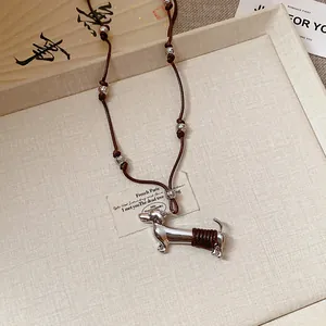Detailed view of a silver-toned dachshund dog pendant with brown woven accents on a cord