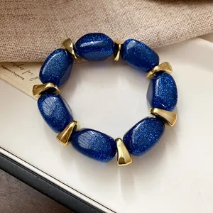 Macro view of sparkly blue acrylic beads and gold spacers on a stylish bracelet.
