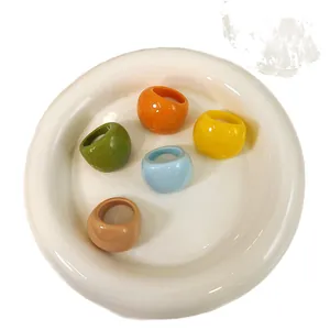 Colorful resin rings set in candy colors on a minimalist white ceramic dish.