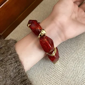 Close-up of a red glitter acrylic beaded bracelet with elegant gold metal spacers on wrist