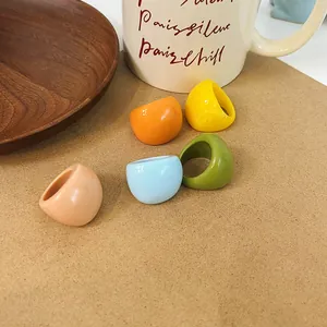 Close-up of colorful chunky resin rings in aesthetic lifestyle setting with wooden plate