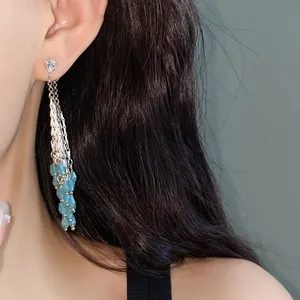 Long elegant silver tassel earrings with blue glass waterdrop beads shown on a female model.