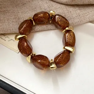 Close-up of brown glitter acrylic beads and gold spacers on an elegant bracelet.