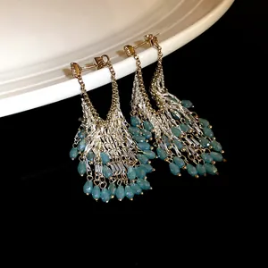 Detailed view of elegant dangling tassel earrings featuring turquoise glass teardrop beads