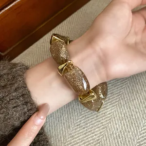 Close-up view of a luxury acrylic oval beaded bracelet with gold glitter on wrist