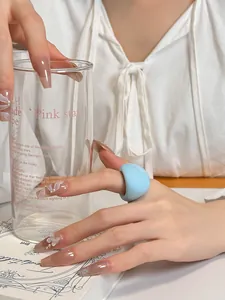 Close-up detail of a chunky light blue resin ring on a hand with elegant long nails
