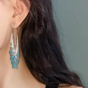 Close-up of elegant silver tassel earrings with vibrant blue glass water drop beads