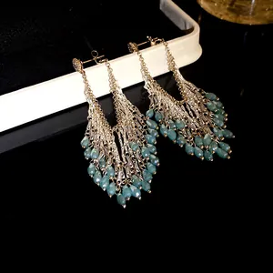 Detailed view of long tassel earrings featuring teal faceted glass drops and silver chains.