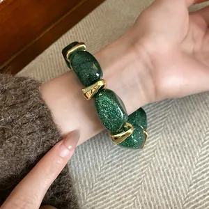 Close-up of green glitter acrylic oval beaded bracelet with gold spacers on wrist