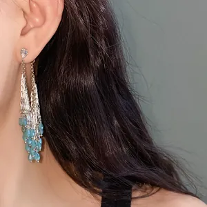 Detail view of long tassel earrings with blue water drop beads and silver chains.