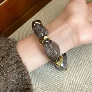 Detail view of an elegant acrylic oval beaded bracelet with shimmering brown glitter beads