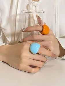 Macro view of bright blue and orange chunky resin rings on fingers with nail art