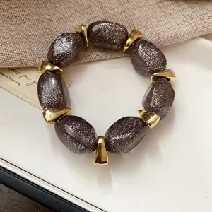 Detailed view of an acrylic beaded bracelet with dark glitter beads and gold spacers