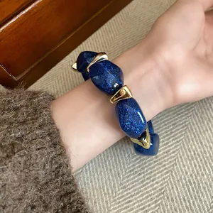 Detailed view of blue glitter acrylic bead bracelet with elegant gold accents on a female wrist