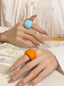Detailed shot of minimalist colorful chunky resin dome rings on manicured fingers
