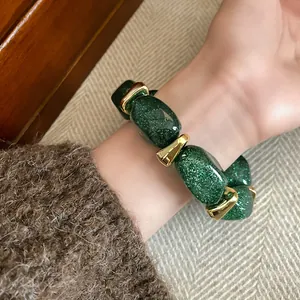 Detailed close-up view of elegant green glitter acrylic beads on a gold-toned bracelet