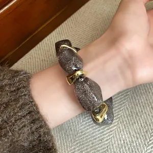 Macro view of a chunky acrylic oval bead bracelet featuring gold accents and glitter