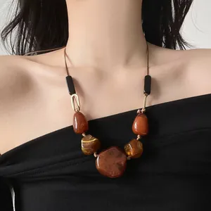 Detailed view of a vintage necklace with irregular amber-style resin pendants on a model.