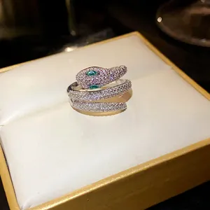 Detailed view of a luxury snake-shaped open ring encrusted with white zirconia and green eyes.